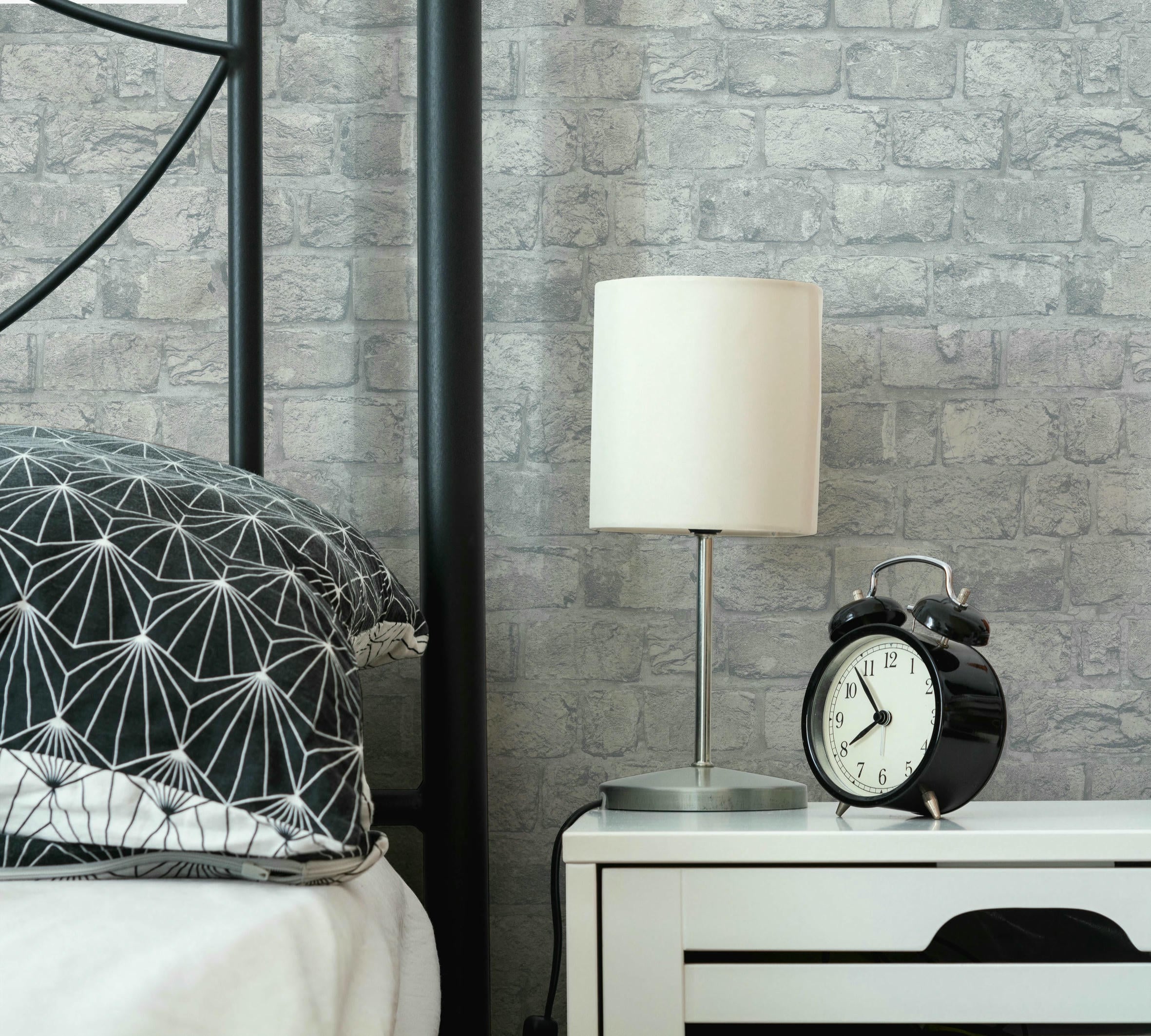 Modern design part of a bedroom with a bed, a pillow, a lamp and an alarm on a nightstand. Waking up concept